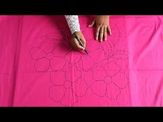 someone is drawing flowers on a pink sheet