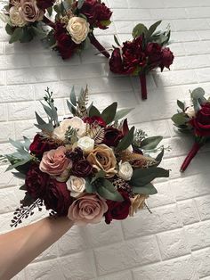 the bridal bouquets are being held by someone's hand against a white brick wall