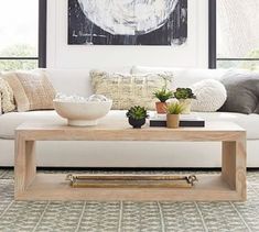 a living room with white couches and plants on the coffee table in front of it