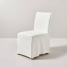 a white chair with a cover on it's back and side rests against a wall