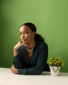 a woman sitting at a table with a potted plant in front of her,