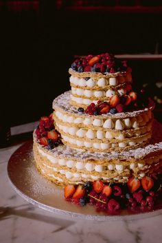 a three tiered cake with fruit on top