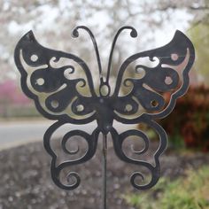 a metal butterfly sculpture sitting on top of a sidewalk