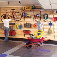 two people working in a garage with various tools on the wall and behind them is a wheelbarrow