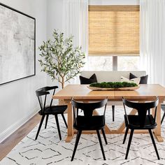 a dining room table with black chairs and a white rug