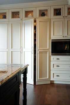 a kitchen with white cabinets and marble counter tops in front of an oven on a wooden floor