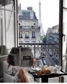 a person sitting in a chair reading a newspaper while holding a tray with food on it