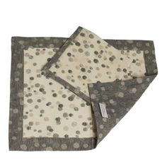 two gray and white polka dot blankets on top of each other, one folded up