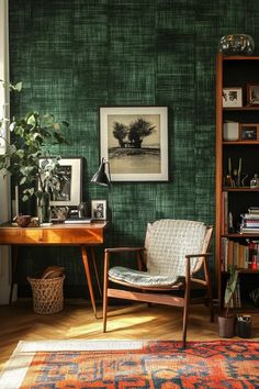 a room with green wallpaper and a chair in front of a bookcase filled with books