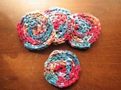 three crocheted coasters sitting on top of a wooden table