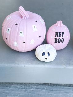 two pink pumpkins with ghost faces painted on them, one is white and the other has black lettering