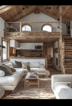 a living room filled with white furniture and wooden stairs leading up to the top floor