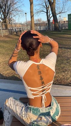 a woman sitting on a bench with her back turned to the camera and holding her hands behind her head