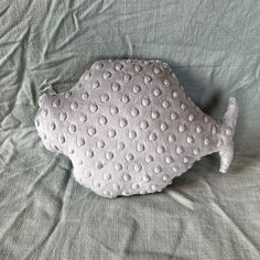 a white fish pillow sitting on top of a bed