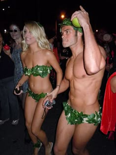 two people dressed up in hula skirts and bikinis, one holding a tennis ball