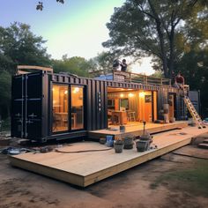 two men are standing on the roof of a shipping container house that is being built