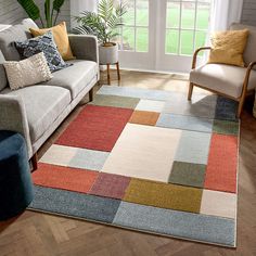 a living room with a couch, chair and rug on the floor in front of a window