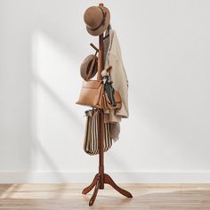 a hat rack with hats and purses on it in front of a white wall