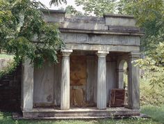 an old building with columns and pillars in the grass