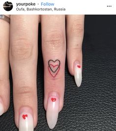 a woman's finger with a heart tattoo on it