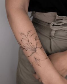 a woman's arm with a flower tattoo on the left side of her arm