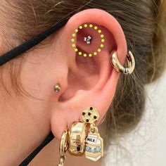 a woman with ear piercings wearing an earring made out of gold and green beads