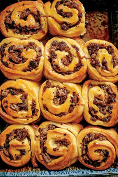 a tray filled with cinnamon rolls covered in icing and toppings on top of each other