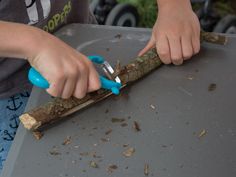 a young boy is using scissors to cut up a tree branch with wood shavings