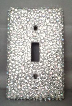 a white light switch cover with lots of small crystals on it's face and bottom