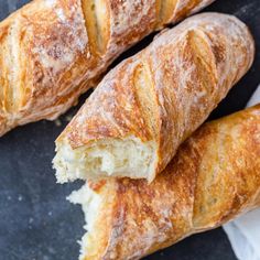 three croissants with powdered sugar on them sitting on a black surface