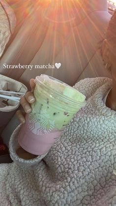 a woman holding a starbucks cup while sitting in a car with the sun shining behind her