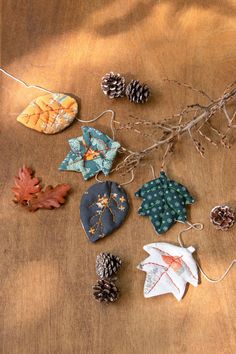 several ornaments are laid out on a table with pine cones and branches in the background