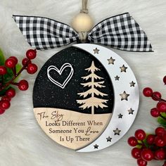 a christmas ornament with a heart on the moon and trees in the background