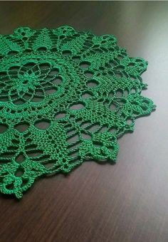 green crocheted doily sitting on top of a wooden table