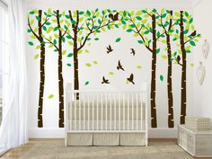 a baby's room with white walls and green leaves on the tree wall decals