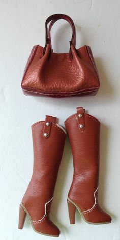 a pair of brown boots and a handbag sitting on top of a white surface