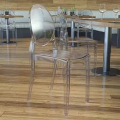 a clear plastic chair sitting on top of a hard wood floor next to a table