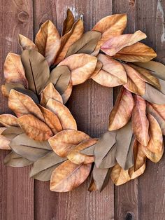 a close up of a wreath on a wooden fence with leaves painted on the front