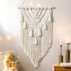 a macrame hanging on the wall next to a table with candles and other decorations