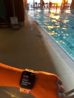 a person wearing an apple watch in front of a swimming pool at sunset or sunrise