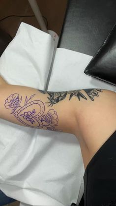 a woman's arm with tattoos on it sitting in front of a white towel