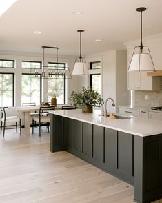 a large kitchen with an island in the middle and two pendant lights hanging from the ceiling