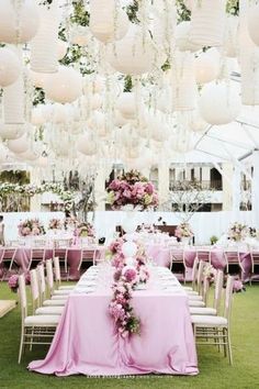 the tables are covered with pink tablecloths and white chandeliers hanging from the ceiling