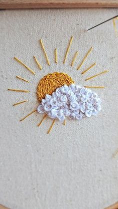 an embroidered sun and cloud in a frame