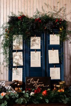 a table topped with lots of cards and greenery next to a blue cabinet covered in notes