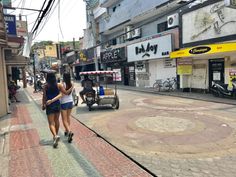 two women walking down the street in front of shops