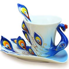 a cup and saucer decorated with peacocks on blue, yellow and white plates