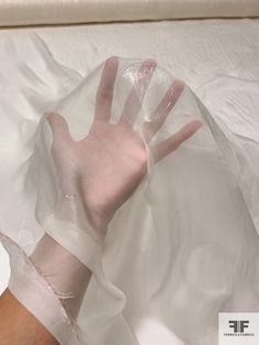 a person's hand wrapped in plastic on top of a white sheeted surface