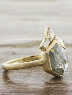 a yellow gold ring with two diamonds on it, sitting on top of a wooden table