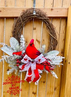 a wreath with a cardinal sitting on top of it next to a wooden fence and door